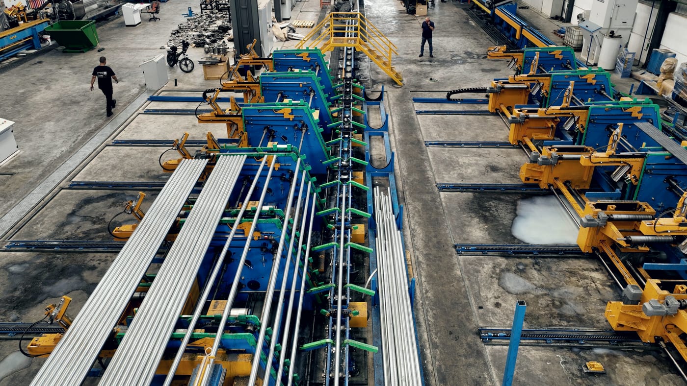 Wide view of a tube and pipe production line inside a large manufacturing plant.